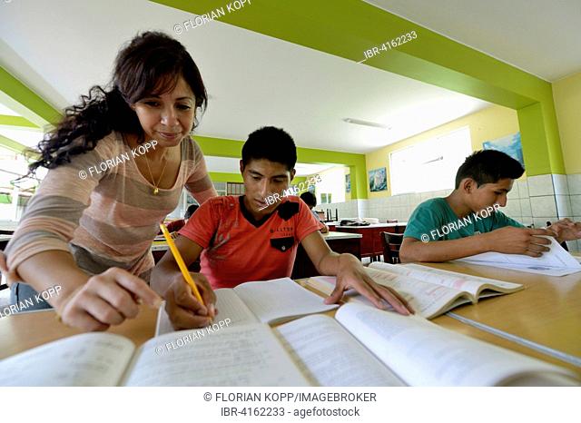 Social worker supporting a teenager, 15 years, former street child, doing homework, Brena, Lima, Peru