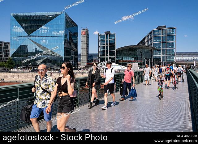 Berlin, Germany, Europe - People, including many visitors and tourists, cross the Gustav Heinemann Bridge with Berlin Central Station and the futuristic 3XN...
