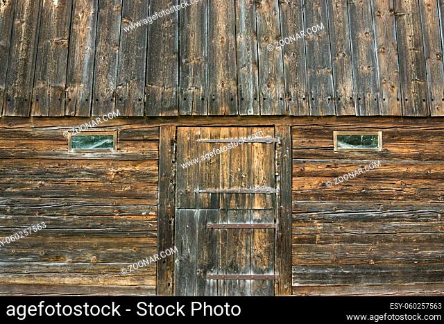 Old wooden barn building with door and windows. Rustic wood background