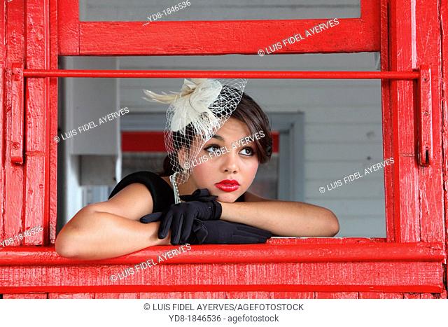 Young woman posing in the window in one of the trains of the Gold Coast Railroad Museum, Miami, Florida, USA