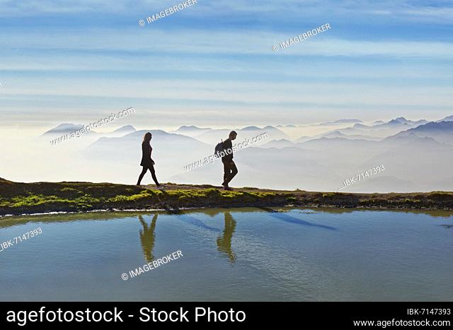 Hikers on a small lake with the peaks of the Lake Garda mountains and Bergamo Alps, Monte Baldo, Malcesine, Verona Italy, Trentino-Alto Adige, Italy, Europe