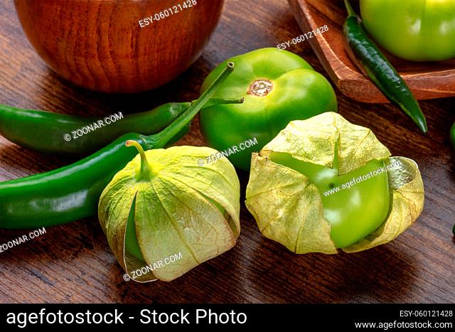 Tomatillos, green tomatoes, and chili peppers. Mexican cuisine ingredients on a dark rustic wooden background