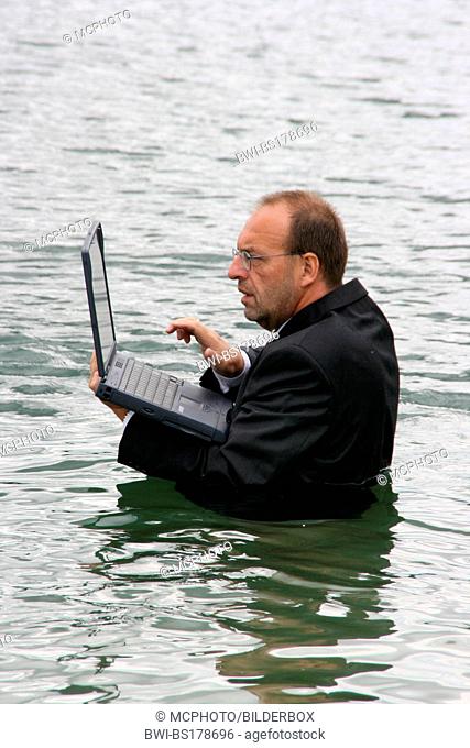 businessman with laptop keep his head above water