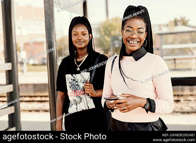 Smiling women standing at train station platform