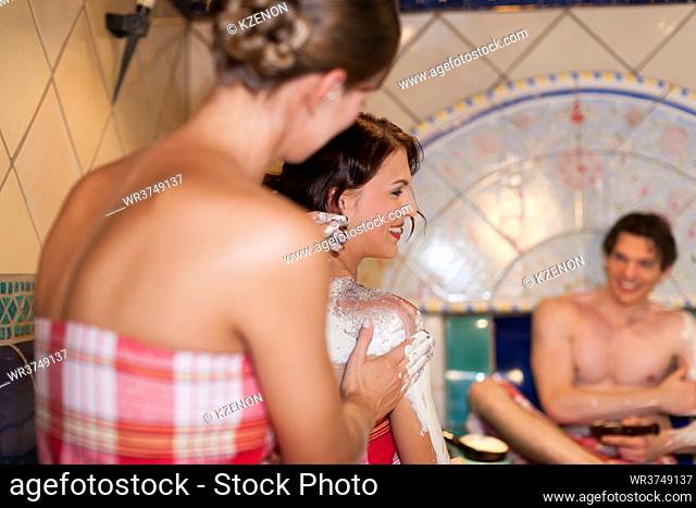 Three friends - two women, one man - doing wellness in the sauna of a thermal bath