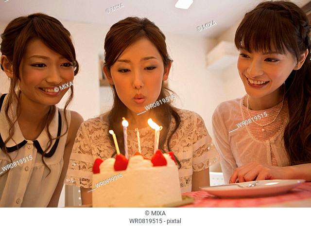 Young Woman Blowing Out Candles on Birthday Cake