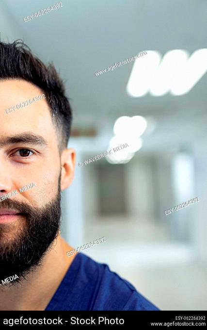 Vertical half portrait of bearded caucasian male healthcare worker in hospital corridor, copy space