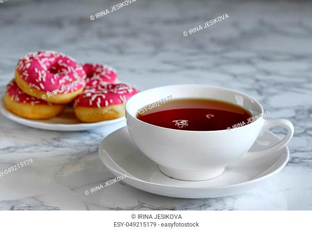 A cup of tea and a saucer with donuts , breakfast time