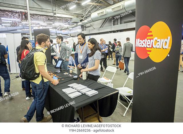 Workers from MasterCard talk to a visitor at the TechDay New York event. Thousands attended to seek jobs with the startups and to network with their peers