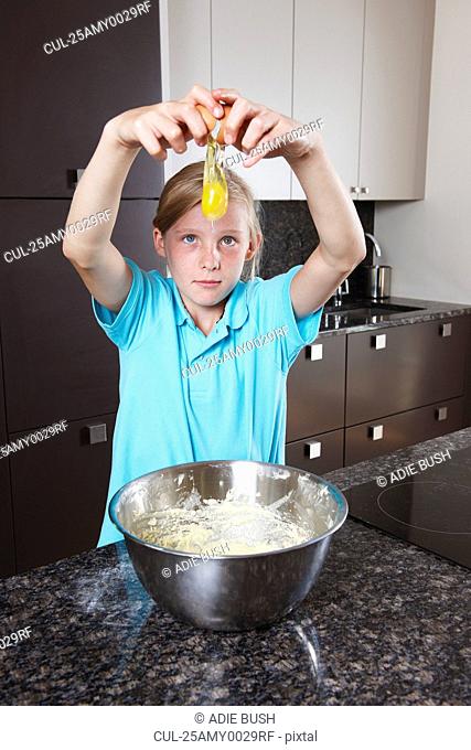 Girl breaking and egg over mixing bowl