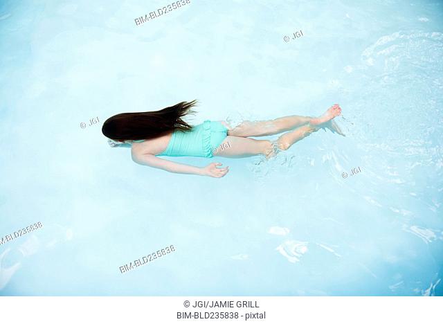 Caucasian girl swimming in swimming pool