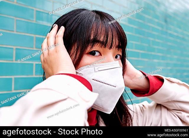 Woman covering ears while wearing protective face mask