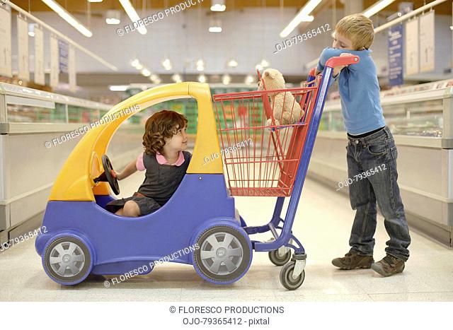 Young boy and young girl in grocery store with shopping cart
