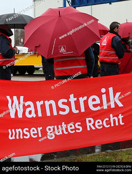 13 December 2023, Mecklenburg-Western Pomerania, Rostock: Employees of wind turbine manufacturer Nordex Energy stand behind a banner reading ""Warning strike -...