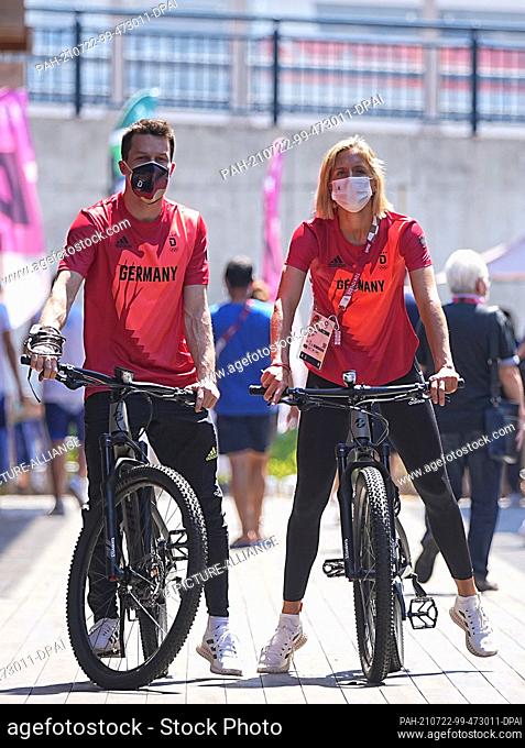 22 July 2021, Japan, Tokio: Water jumper Patrick Hausding (l) and beach volleyball player Laura Ludwig arrive by bicycle at the press conference of the German...