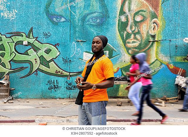 Senegalese graffiti artist Docta beside a collective mural in Medina district, Dakar, Senegal, West Africa