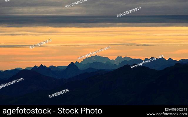 Bright lit yellow morning sky over Mount Grosser Mythen, Saentis and other mountains in the Swiss Alps