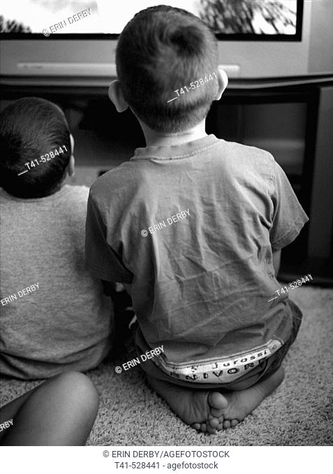 Two brothers sit side by side as they play video games
