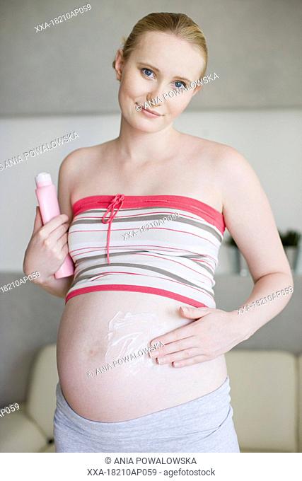 pregnant woman applying cream on belly