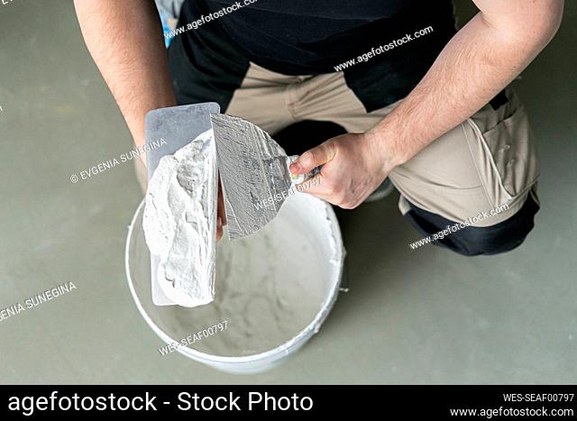 Man with work tool and plaster at home