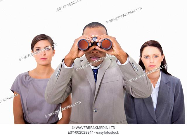 Businessman with colleagues using binoculars against a white background