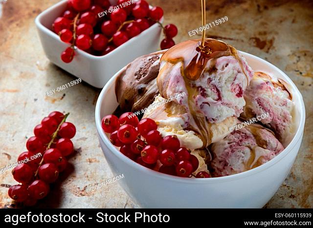 homemade ice cream in white bowl with currant on steel plate