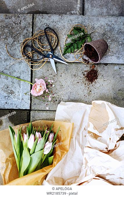 Directly above shot of tulip bouquet with scissors and pot on concrete floor