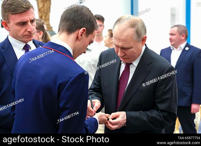 RUSSIA, MOSCOW - DECEMBER 18, 2023: Russia's President Vladimir Putin (R front) signs an autograph during a meeting with winners and mentors of the...