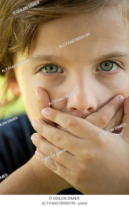 Boy covering mouth with hands