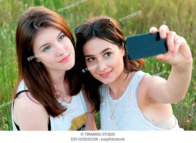 Two teenage girls taking selfie and having fun outdoors