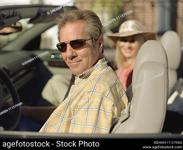 Middle-aged couple sitting in convertible