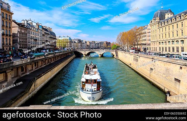 Paris / France - April 5, 2019: Beautiful cityscape of Paris, Saint-Michel bridge across Seine river and a tourist ship with tourists