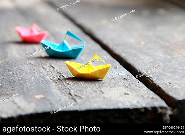 Set of multi-colored origami boats on wooden table. Paper ships