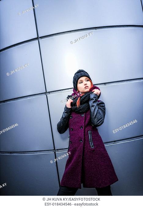 Attractive woman wearing winter coat, rounded wall on background and low angle view