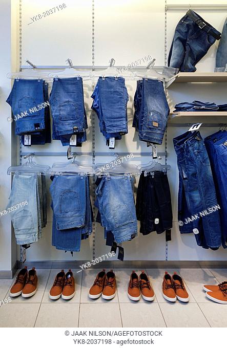 Jeans, trousers and shoes in retail shop interior. Store display with rack, shelf