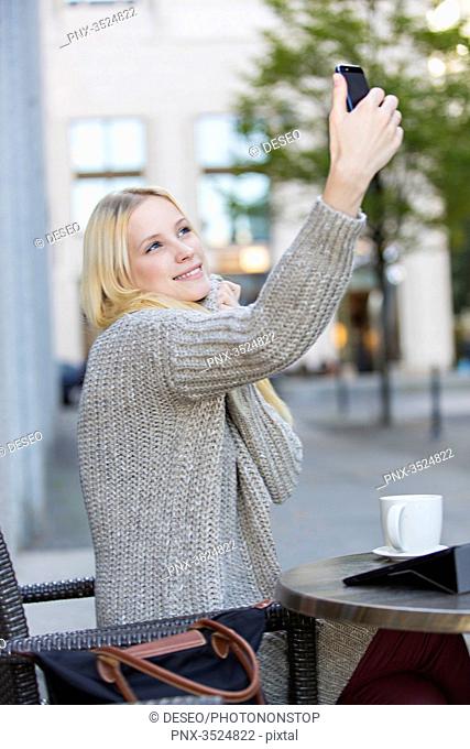 Pretty young woman doing a selfie in a Cafe in city center