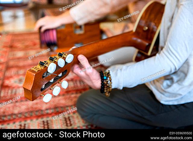 Closeup of two people playing classical guitar with nylon strings and harmonium together as sacred music for calm music during meditation