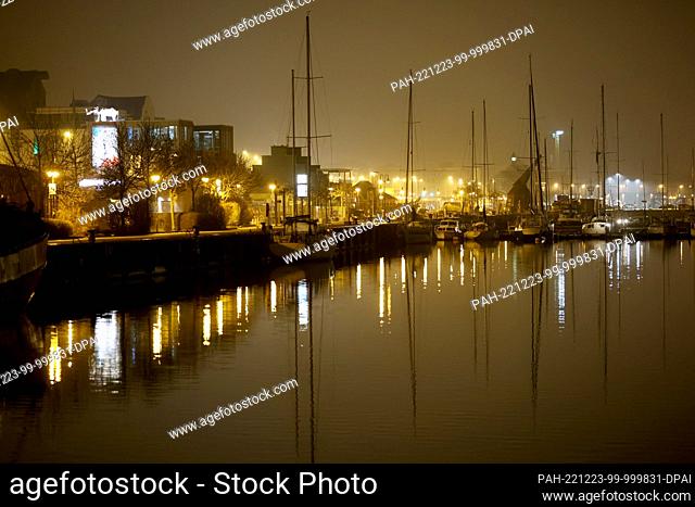 23 December 2022, Mecklenburg-Western Pomerania, Rostock: Lights are reflected in the water in the city harbor on the Warnow River