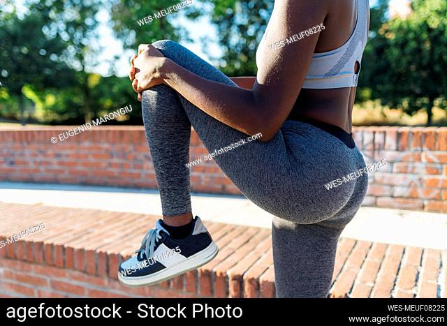 Active young sportswoman stretching leg