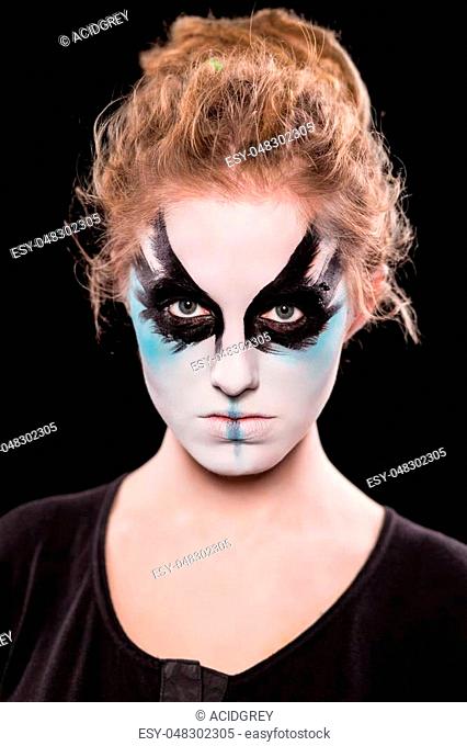 Portrait of young woman with painted face for Halloween. Isolated on black