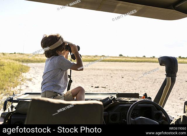 A six year old boy looking through binoculars across a salt pan