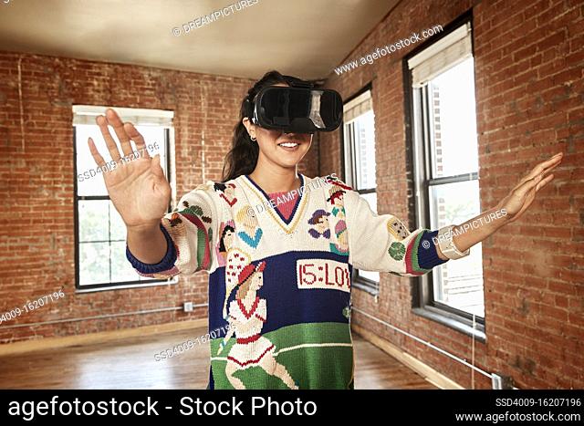 Young ethnic woman wearing VR headset in empty loft