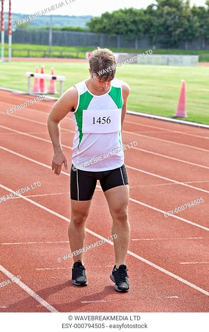 focused sprinter ready to run standing on the starting line in a stadium