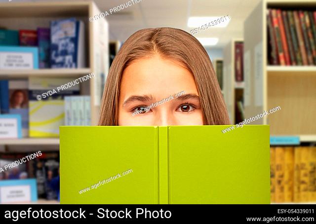 teenage student girl hiding over book at library