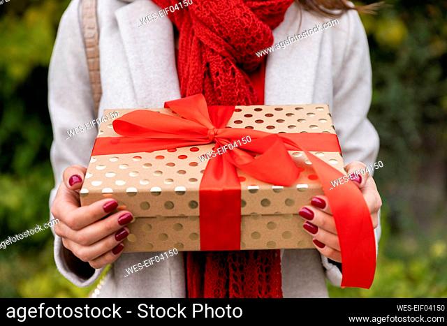 Young woman holding Christmas present with red bow