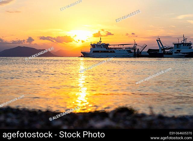 Ships and boats in the harbour at sunset at the island of Evia in Greece in town called Pefki