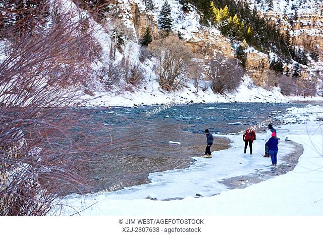 Glenwood Springs, Colorado - Visitors walk on the winter ice at the edge of the Colorado River in Glenwood Canyon