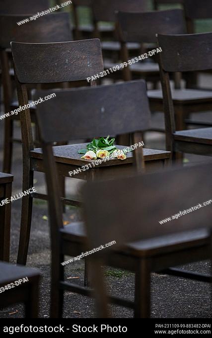 09 November 2023, Saxony, Leipzig: Three white roses lie on a bronze chair in Leipzig's synagogue memorial. On this day, vigils