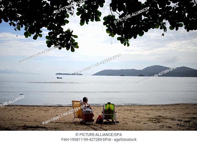 28 January 2018, Brazil, Paraty: Tourists sit on the beach in the sun. Photo: Britta Pedersen/dpa-Zentralbild/ZB. - Paraty/Brazil