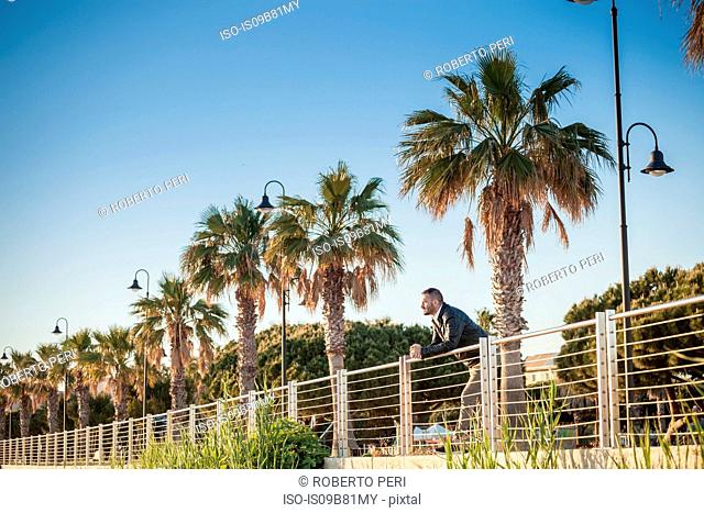 Man leaning against railings looking away, Cagliari, Sardinia, Italy, Europe
